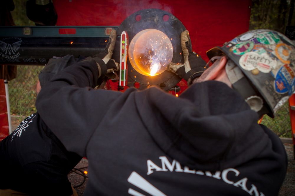 Pipefitter welding a pipe flange on site