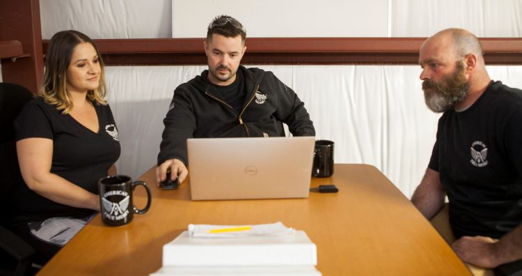 Three team members reviewing plans on a laptop at a meeting table
